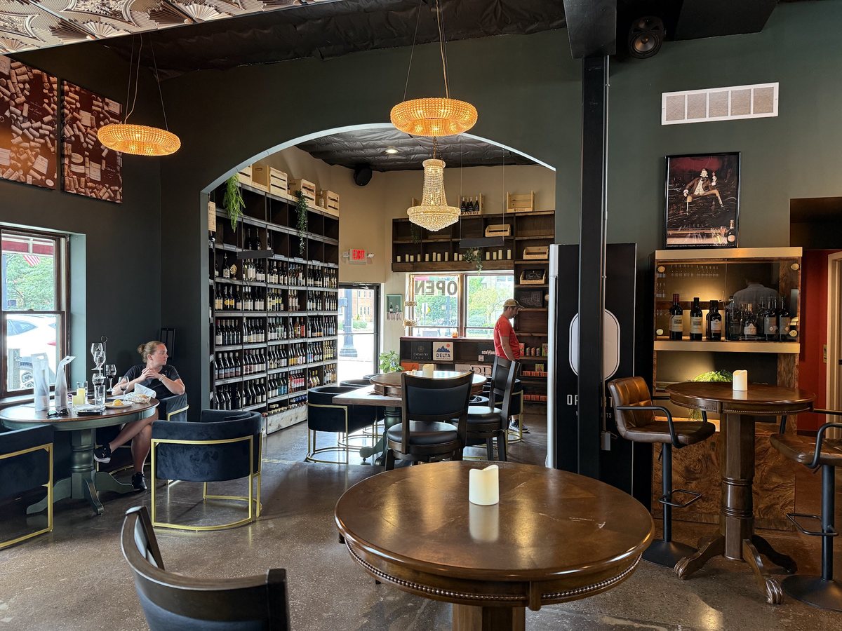 The Open BTL lounge: round tables, velvet chairs, and an arched doorway to the bottle room